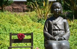 The Comfort Woman statue, with bird on shoulder, beside an empty chair symbolizing survivors who are of an old age without having yet witnessed judgement, in Glendale, California on September 9, 2014, a day after reports that opponents of the statue have appealed the August decision by U.S District Judge Percy Anderson against removing the memorial dedicated to women who were coerced into sexual slavery during World War II by Japan, ruling the 1,100-pound memorial did not cause harm to the plaintiffs nor break any laws. The statue was installed at Glendale's Central Park in July 2013. AFP PHOTO / Frederic J. BROWN (Photo credit should read FREDERIC J. BROWN/AFP/Getty Images)